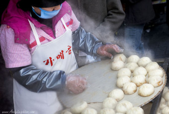 A women shop assistant dressed in the shops pink colour prepares the freshly steamed king dumplings or mandu ready for sale. Namdaemun Market, Seoul, South Korea