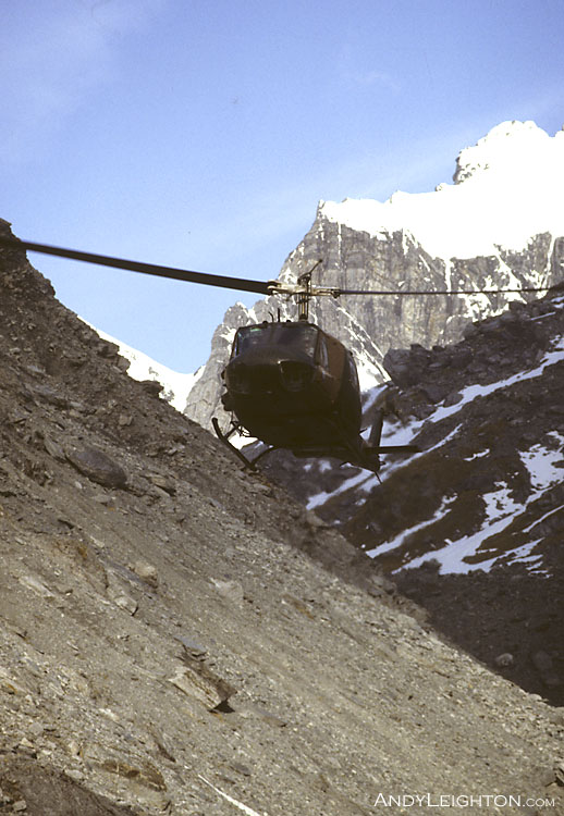 An Air Force Iroquois helicopter coming in to land and pick up searchers in a mountainous area of Westland. A slight bending of the blades can be seen as the helicopter flares for landing. New Zealand